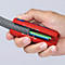 Hand houdt een kabelstripgereedschap vast. Rode tang, grijze buis, gekleurde kabels zichtbaar.