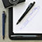 Trois stylos à bille sur une table, dont un noir, un bleu et un gris.
