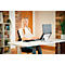Une femme sourit en travaillant à un bureau réglable en hauteur, un ordinateur portable sur un support, entourée de matériel de bureau.