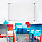 Une salle de classe avec un tableau blanc, des chaises colorées et des coussins.