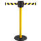 Yellow and black retractable belt stanchion. The stanchion has a round black base, a yellow pole, and a black head with the belt outlet.