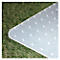 Tapis en plastique transparent gris clair avec des clous sur l'herbe. Forme angulaire avec un coin arrondi.