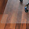 Tapis de protection de sol transparent sur un plancher en bois, une chaise de bureau roule dessus.