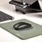 Une souris d'ordinateur noire est sur un tapis de souris vert à côté d'un clavier et d'un support pour ordinateur portable.