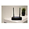 Schwarzer Router mit zwei Antennen. Er steht auf einer weiÃŸen OberflÃ¤che neben einer Topfpflanze.
