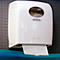 Dispensador de toallas de papel blanco sobre chapa perforada gris. Se saca papel. Logotipo 'Kimberly-Clark Professional'.