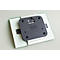 Gray bracket with black plastic plate on glass plate. Holes are attached at the corners.