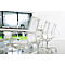 White office chairs around a table with glasses and a carafe, bright room, large windows.