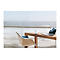 Un ordinateur portable et un routeur Wi-Fi sont posÃ©s sur une table en bois face Ã  la mer. Une chaise est devant.