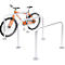 An orange bike rests in a silver bike rack. Two more racks next to it.