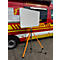 Ein leeres Whiteboard auf einem orangefarbenen Dreibeinstativ vor einem rot-gelben Einsatzleitfahrzeug der Feuerwehr.