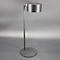 Un lampadaire argenté avec une base ronde, une tige fine et un abat-jour cylindrique.