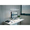 Bureau avec ordinateur, lampe, plante et tasse à café. Environnement de travail lumineux et minimaliste.