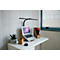 Un ordinateur portable avec support et lampe sur un bureau, à côté une plante et un bac à papier.