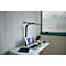 Schreibtisch mit Laptop, Lampe, Pflanze und Becher. Fenster im Hintergrund, helle Holzoptik Wand.