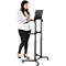 Une femme se tient debout devant un bureau d'ordinateur portable à hauteur réglable, en train de taper. Le bureau est noir, la femme porte du noir et blanc.
