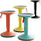 Four height-adjustable standing stools in different colors: orange, yellow, turquoise and black. With red loops and gray seats.