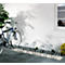 Blue bicycle in a bike rack. The rack is mounted on a paved path in front of a white wall with a window.