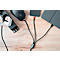 On a wooden surface, there is a power adapter, a mouse, a smartphone, and a tablet. All devices are connected via cables.
