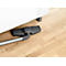 A vacuum cleaner head cleans the floor under a white sofa. The floor has a light wood pattern.