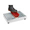A black boot is standing on a metal shoe cleaning mat with a red brush.