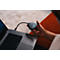 Person hält einen dreieckigen, grauen Barco ClickShare Button mit leuchtendem Ring an einem Laptop.