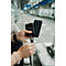 Person lädt ein schwarzes Smartphone mit einer Powerbank an einem Bahnhof.