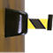 Black barrier tape with yellow stripes, attached to wood.