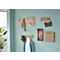 Hölzerne Wandgarderobe mit Kleidung und Accessoires an einer hellblauen Wand.