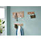 Holzgarderobe mit Kleidung und Accessoires an hellblauer Wand.