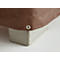 Brown tarpaulin with red seam, metal eyelet, on gray cuboid.