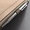 Close-up van een zilveren pen die in een beige notitieboek ligt.