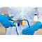 Person in white lab coat and blue gloves cuts colored tabs off a piece of fabric with scissors.