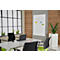 Conference room with table, chairs, and flipchart. Window in background. Colorful graphic on whiteboard.