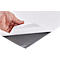Hand lifting a white sheet of paper, revealing a smooth, grey surface.