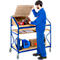 A man in blue overalls opens a serving cart. There are tools and accessories on the cart.