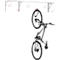Bike on a wall mount. Gray mount with red hooks. Bike is vertically suspended.