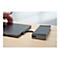 Un ordinateur portable gris et un hub gris sont reliés par un câble, sur une table en bois clair. Une main s'approche de l'ordinateur portable.
