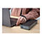 Une personne connecte un connecteur USB-C à un ordinateur portable. Une station d'accueil noire se trouve à droite. Le fond est une table en bois.