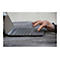 Gros plan d'une main touchant un pavé tactile d'ordinateur portable. La main a des ongles peints en foncé et une bague.