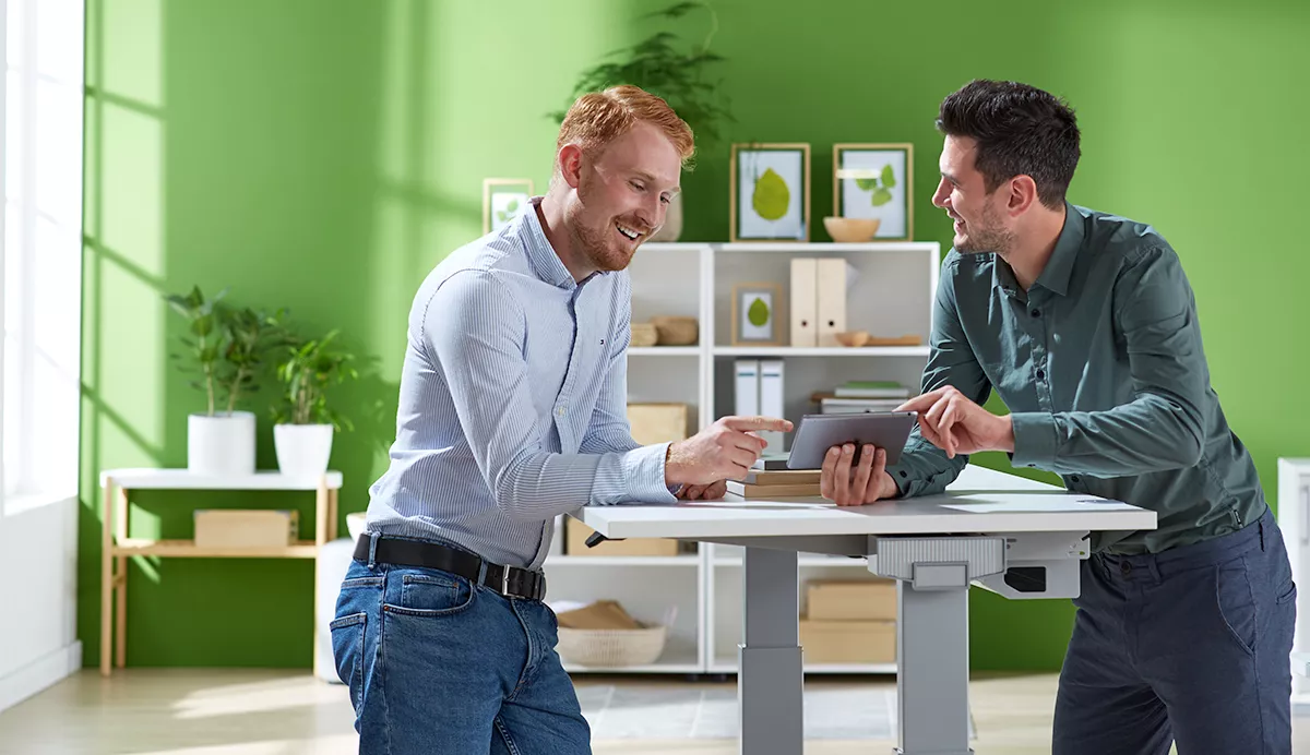 2 mannen zijn in gesprek. De ene man geeft advies aan de andere man en toont iets op zijn mobiele telefoon