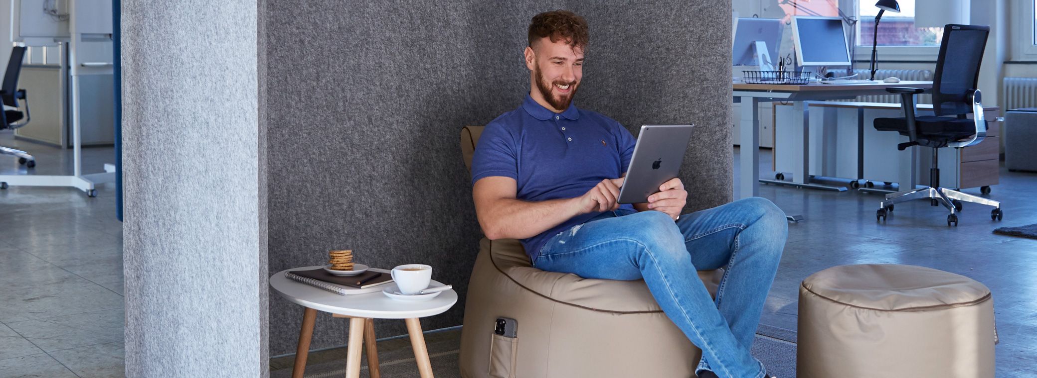Ein Mitarbeiter arbeitet in Ruhe mit seinem Tablet auf einem Sitzsack.
