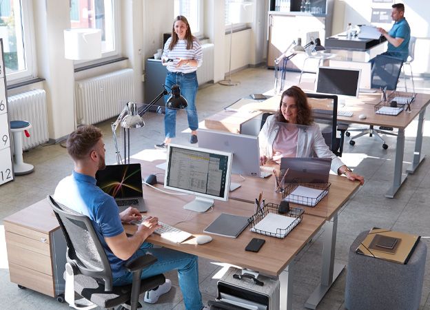 Kantoor met flexibele desk-sharing werkplekken en vier werknemers.