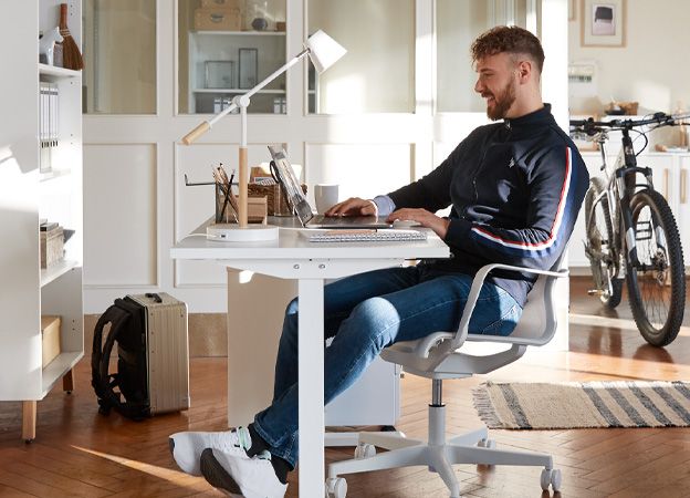 Werk in een thuiskantoor met in hoogte verstelbaar bureau en bureaustoel.
