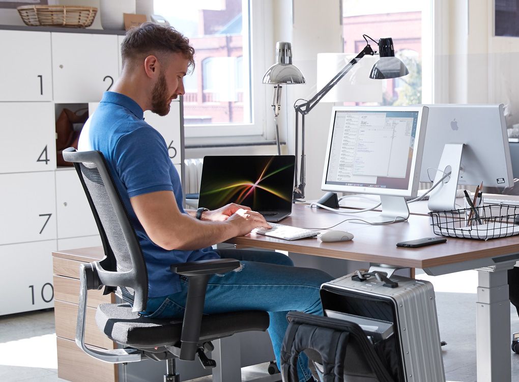 L'employé travaille dans un bureau en desk sharing avec un équipement flexible.