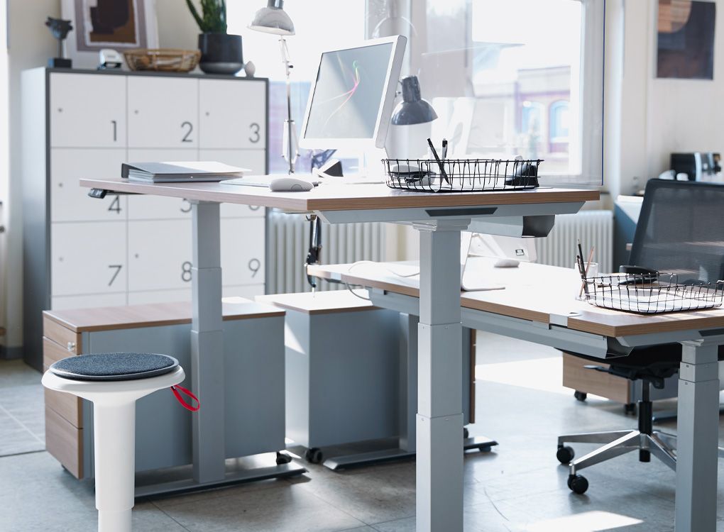 Ergonomischer Hocker und höhenverstellbare Schreibtische im Büro.
