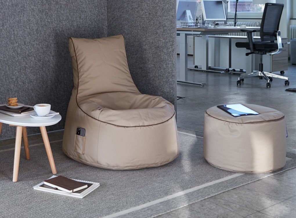 Espace de repos pour le travail hybride au bureau avec pouf et table.