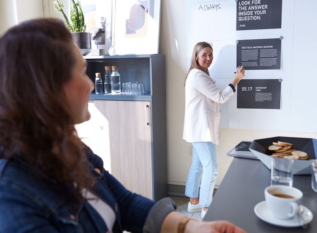 Een personeelslid legt iets uit aan een collega met behulp van een informatiebord.