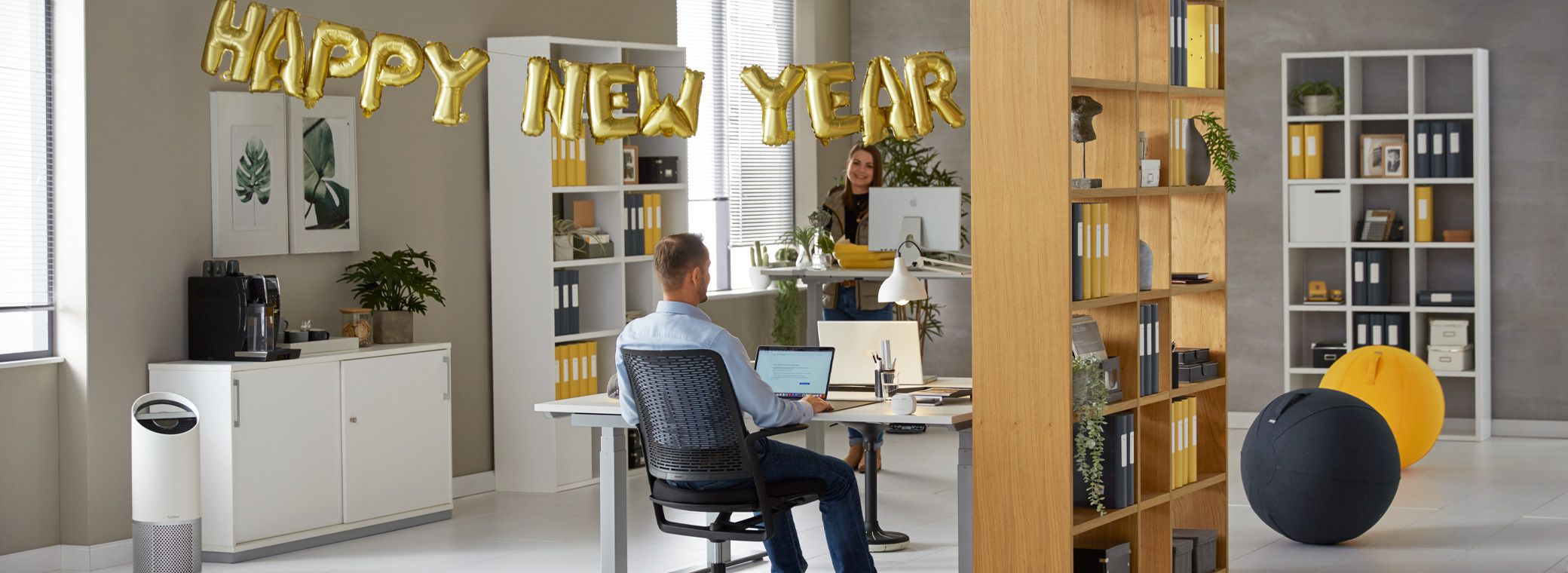 Aufgeräumtes Büro mit Regalen, Aktenordnern und Partydekoration für Neujahr