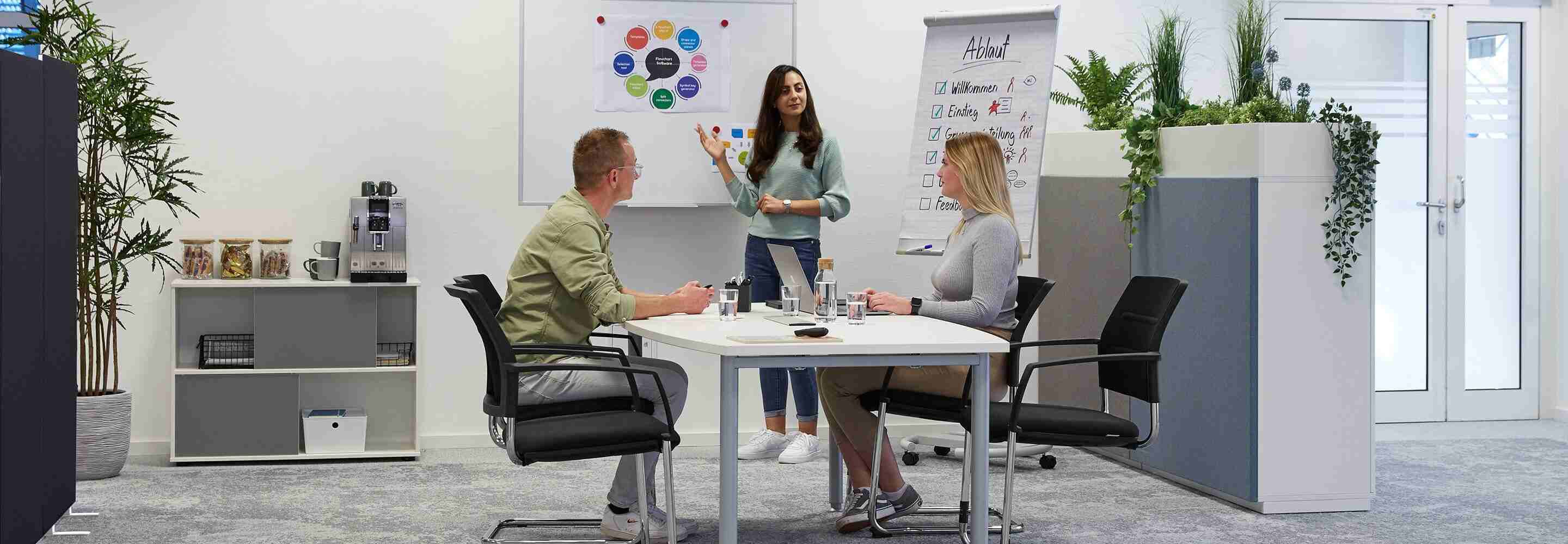 Drie mensen in een vergaderruimte in een workshopsituatie